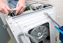 Ein Mann repariert eine Waschmaschine - Andrea Warnecke/dpa-tmn