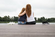 Zwei Frauen sitzen auf einem Steg am See - Christin Klose/dpa-tmn