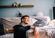 Ein Mann sitzt vor dem PC und schaut aus dem Fenster - Zacharie Scheurer/dpa-tmn