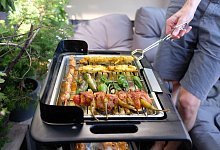 Ein Mann grillt mit einem Elektrogrill auf einem Balkon - Laura Ludwig/dpa-tmn/dpa