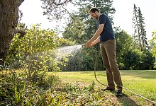 Ein Mann wässert Pflanzen im Garten - Christin Klose/dpa-tmn