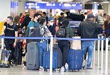 Passagiere warten auf dem Flughafen in Frankfurt am Main auf ihren Check-In. - Boris Roessler/dpa