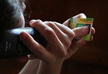 Ein Mann hält beim Telefonieren eine Gesundheitskarte - Karl-Josef Hildenbrand/dpa/dpa-tmn