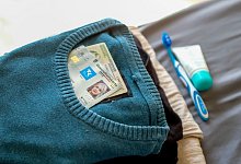 Personalsausweis und Versichtertenkarte liegen auf Kleidung - Laura Ludwig/dpa-tmn/dpa