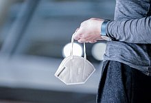 Eine Frau hält einen Mund-Nasen-Schutz in der Hand - Kay Nietfeld/dpa/dpa-tmn