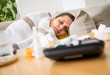 Eine Frau liegt krank auf einem Sofa - dpa