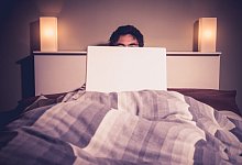 Young man sitting in bed and using laptop ,model released, Symbolfoto; Jung Mann sitzend in Bett und - IMAGO/ingimage