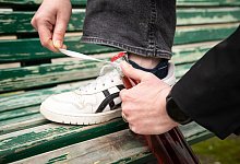 Schn&uuml;rsenkel wird um den Kronkorken einer Flasche gelegt - Christin Klose/dpa-tmn