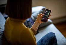 Eine Frau ruft Aktienkurse auf einem Smartphone auf - Fabian Sommer/dpa/dpa-tmn