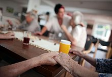 Bewohner in einer betreuten Pflege-WG halten sich an den Händen - Oliver Berg/dpa/dpa-tmn