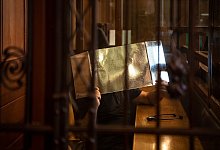 Der Angeklagte h&auml;lt sich in einem Gerichtssaal eine Pappe vor sein Gesicht. - Paul Zinken/dpa