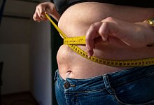 Eine Frau mit &Uuml;bergewicht h&auml;lt ein Ma&szlig;band um ihren Bauch. - Pia Bayer/dpa/dpa-tmn