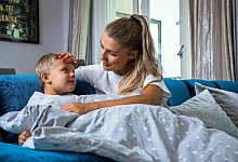 Eine Mutter legt ihre Hand auf die Stirn ihres Sohnes - Christin Klose/dpa