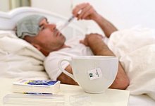 Ein kranker Mann liegt im Bett und misst Fieber. - Andreas Gebert