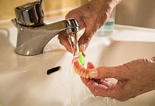 Eine Frau reiniht eine Zahnprothese - Christin Klose/dpa-tmn