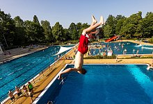 Im Freibad in Forst (Lausitz) springt ein Badegast bei etwa 35 Grad Celsius im Schatten von der 5-meter-Plattform des Sprungturms ins Becken. - Frank Hammerschmidt/dpa