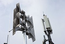 Eine Alarmsirene auf dem Dach eines Mehrfamilienhauses neben Mobilfunkantennen. - Soeren Stache/dpa