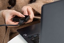 Eine Frau sichert Fotos auf ihrem Computer - Foto: Christin Klose/dpa-tmn