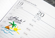 Eine Palme und das Wort Urlaub stehen in einem Planer - Christin Klose/dpa-tmn