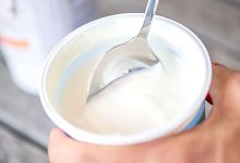 Mann h&auml;lt Becher mit veganem Joghurt-Ersatz in der Hand - Zacharie Scheurer/dpa-tmn