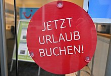 Ein Schild mit der Aufschrift «Jetzt Urlaub buchen!» - Peter Kneffel/dpa/dpa-tmn
