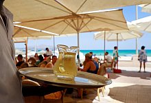 Ein Kellner serviert an einem mallorquinischen Strand einen Wein - Clara Margais/dpa/dpa-tmn