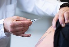 Eine Ärztin hält eine Fertigspritze mit einem Impfstoff - Sebastian Kahnert/dpa/dpa-tmn