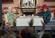 Die Zuschauer sehen auf einer gro&szlig;en Leinwand w&auml;hrend der Platin-Party vor dem Buckingham-Palast Elizabeth II. beim Tee mit Paddington Bear. - Victoria Jones/PA/dpa