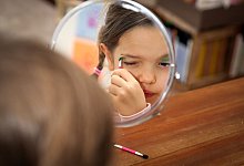 Ein Mädchen schminkt sich mit Kinderschminke - Mascha Brichta/dpa-tmn