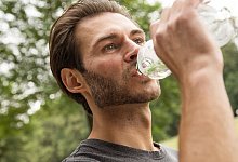 Mann trinkt Wasser aus einer PET-Flasche - Christin Klose/dpa-tmn