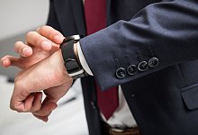 Mann im Anzug schaut auf seine Armbanduhr - Christin Klose/dpa-tmn