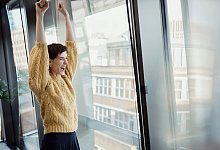 Frau reißt in einem Büro begeistert die Arme nach oben - Phillip Waterman/Westend61/dpa-tmn