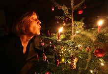 Eine Frau bl&auml;st an einem Weihnachtsbaum eine Kerze aus - Karl-Josef Hildenbrand/dpa-tmn
