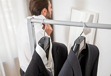 Mann beim Ankleiden hinter Kleiderstange - Christin Klose/dpa-tmn