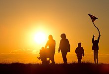 Eine Familie geht dem Sonnenuntergang entgegen - Christian Charisius/dpa/dpa-tmn