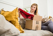 Eine Frau packt Kleidung aus einem Karton aus - Christin Klose/dpa-tmn