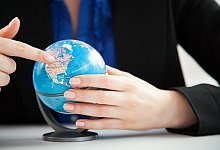 Eine Frau schaut auf einen kleinen Globus im Büro - Christin Klose/dpa-tmn