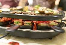 Auf der Platte wird gegrillt, in den Pf&auml;nnchen raclettiert - beide Diszplinen beherrschen laut Stiftung Warentest nur wenige Raclettes gleich gut. - Daniel Maurer/dpa-tmn