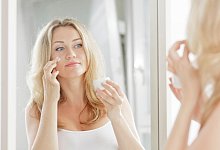 Eine Person vorm Spiegel benutzt Creme - Monique W&uuml;stenhagen/dpa-tmn/dpa