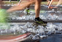 Ein Jogger l&auml;uft &uuml;ber benutzte Wasserbecher - Gregor Fischer/dpa/dpa-tmn