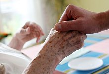 Eine Pflegerin hält die Hand einer Seniorin - Oliver Berg/dpa/dpa-tmn