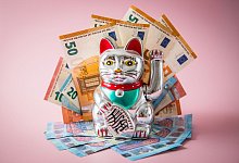 Japanische Glückskatze Maneki-neko mit Geldscheinen - Christin Klose/dpa-tmn