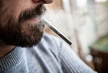 Ein Mann h&auml;lt eine E-Zigarette im Mund. Wegen anstehender Steuererh&ouml;hungen ziehen Hersteller und H&auml;ndler von E-Zigaretten vor das Bundesverfassungsgericht. - Fabian Strauch/dpa