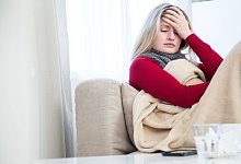 Eine Frau sitzt krank auf einem Sofa - Christin Klose/dpa-tmn