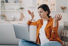 Puzzled european woman with laptop is talking at internet meeting and telling a problem. - Verbraucherzentrale NRW