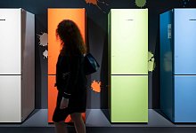 Eine Frau geht an bunten K&uuml;hlschr&auml;nken vorbei - Florian Schuh/dpa-tmn