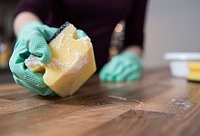 Eine Frau reinigt die Arbeitsfläche einer Küche - Franziska Gabbert/dpa-tmn