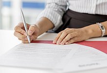 Frau unterschreibt ein Arbeitszeugnis - Monique Wüstenhagen/dpa-tmn