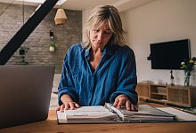 Frau schaut in einen Ordner mit Unterlagen - Zacharie Scheurer/dpa-tmn