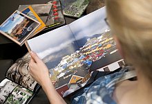 Eine Frau schaut sich ein Fotobuch an - Foto: Mascha Brichta/dpa-tmn